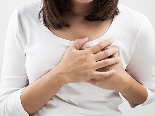 Mother holding her breast in pain, one of her postpartum body changes